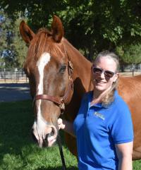 Dr. Julie Dechant standing with CEH herd horse Georgio