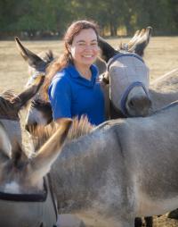 Dr. Lais Costa in a field with several donkeys